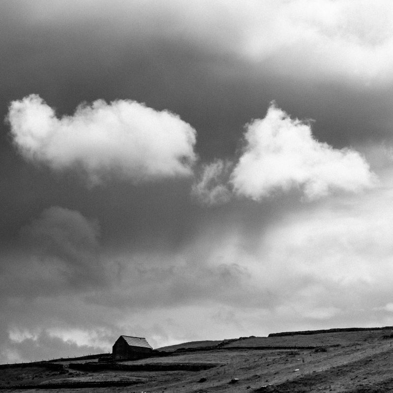 black and white clouds above house in fields