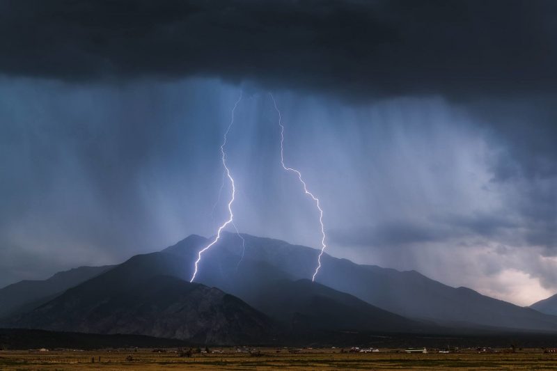 two bolts of lightning strike a mountain in a storm