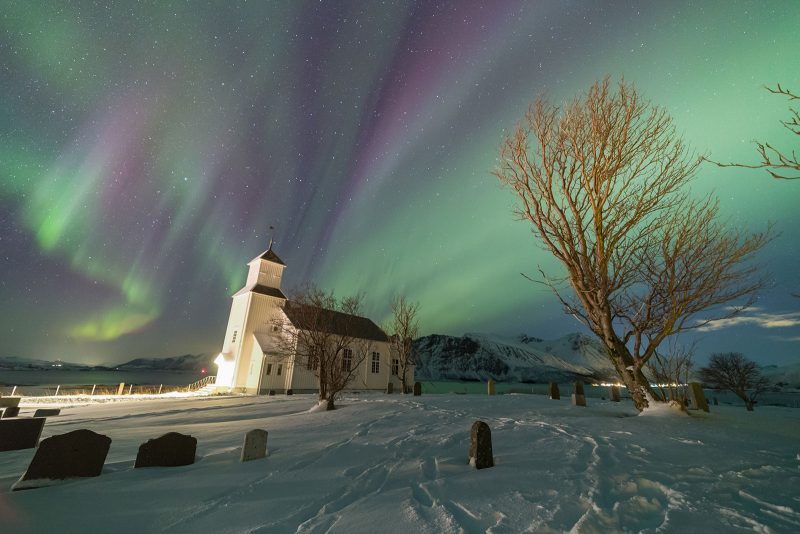 Colorful Aurora lights up the sky above the church 