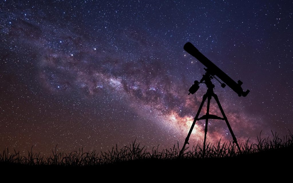 telescope silhouetted against the Milky Way galaxy